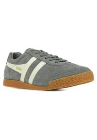 Sneaker in suede grigia con strisce laterali bianche, suola in gomma e suola esterna in pelle marrone testurizzata. Presenta il marchio Gola in oro sul lato.