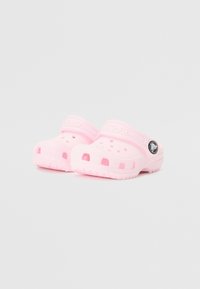 Pink clogs made of lightweight material, featuring ventilation holes, a textured sole, and a heel strap for secure fit.