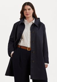 Ναυτικό πα trench coat με χαλαρή εφαρμογή, μεγάλο γιακά και κουμπιά μπροστά. Διαθέτει κουμπιά από χελώνα και μαλακό, ανθεκτικό ύφασμα.