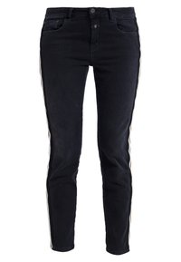 Jeans negros de corte slim, con franjas laterales en blanco y marrón claro, fabricados en denim de textura suave y diseño estándar de cinco bolsillos.