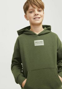 Sudadera verde con un bolsillo canguro en el frente, puños acanalados y un parche de logo. Material suave con un corte holgado, diseño minimalista.