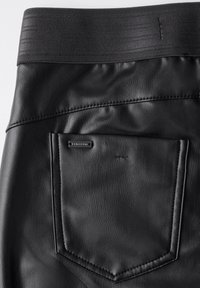 Svarta läderbyxor med en bred elastisk midjeband. Har en liten bakficka med en metallbricka. Slät textur med subtil lyster.