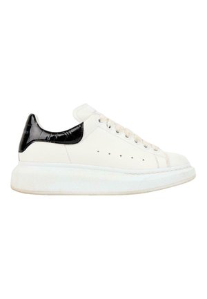 Baskets basses blanches avec languette de talon noire texturée, lacets blancs et semelle blanche épaisse, vues de l'extérieur.
