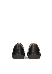 Zapatos de cuero negro con punta redondeada, diseño minimalista, textura suave y suela de goma. Presentan un sutil detalle de costura en la parte trasera.