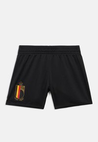 Μαύρα αθλητικά σορτς με ελαστική μέση και μεγάλο έμβλημα με χρυσές λεπτομέρειες, που περιλαμβάνει ένα στέμμα και τα χρώματα της βελγικής σημαίας.