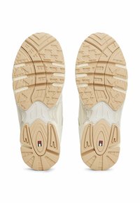 Suola di scarpa sportiva beige con superficie in gomma testurizzata, caratterizzata da scanalature profonde e un logo sul tallone per trazione e supporto.