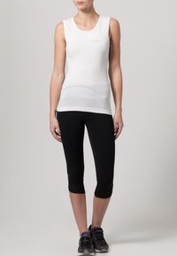 Top atletico senza maniche bianco con scollatura tonda, abbinato a leggings capri neri. Entrambi realizzati in tessuto elasticizzato e traspirante.
