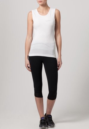 Top atletico senza maniche bianco con scollatura tonda, abbinato a leggings capri neri. Entrambi realizzati in tessuto elasticizzato e traspirante.