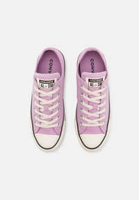 Sneaker in tela viola con lacci bianchi, punta in gomma e dettagli neri. Presenta una patch con logo e tessuto testurizzato.
