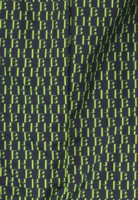 Marineblauem Stoff mit einem Muster aus abwechselnden grünen Buchstaben "B"-Formen und vertikalen Linien. Glatte Textur, gleichmäßig verteiltes Design.