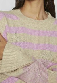 Beige och rosa randig tröja med rund halsringning, texturerad stickad mönster och lös passform. Ärmarna är något överdimensionerade.