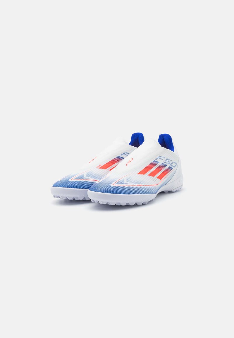 Botas de fútbol blancas y azules con parte superior texturizada, cuentan con acentos rojos y un diseño sin cordones para facilitar su uso. Tachuelas de tracción en la suela.