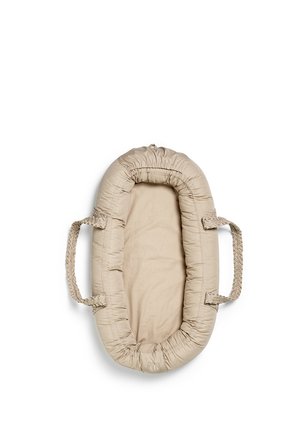 Beige polstret babynest med flettede håndtag på hver side, designet til spædbarns komfort og bærbarhed, vist mod en hvid baggrund.