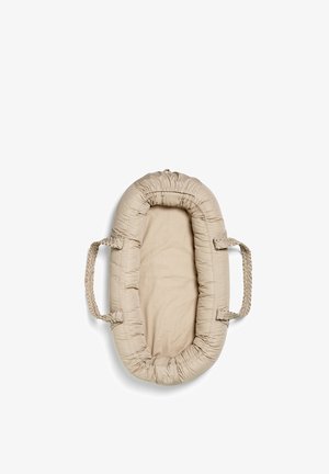 Beige polstret babynest med flettede håndtag på hver side, designet til spædbarns komfort og bærbarhed, vist mod en hvid baggrund.
