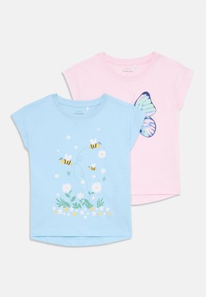 Duas t-shirts: uma azul clara com estampa de abelhas e flores, outra rosa com gráfico de uma borboleta. Ambas têm mangas curtas e decote redondo.