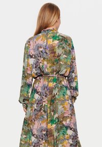 Rochie multicolor dintr-un material moale și fluid, cu un model floral pictural, mâneci lungi și talie strânsă cu o curea.