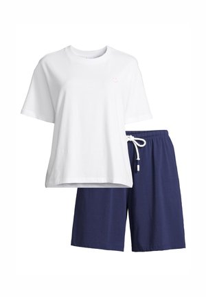 Valkoinen lyhythihainen T-paita, jossa pieni vaaleanpunainen hymyilevä kuvio, ja tummansiniset nauhakujaiset shortsit, rento kesäasu.