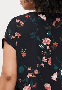Black blouse with short sleeves, featuring a floral pattern in pink, white, and green. Lightweight fabric with a relaxed fit.