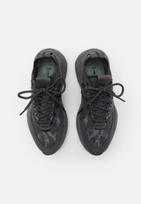 Chaussures de sport noires avec un dessus en maillage texturé, une semelle en caoutchouc robuste et des semelles intérieures à motifs. Présente des accents gris et des lacets ronds.