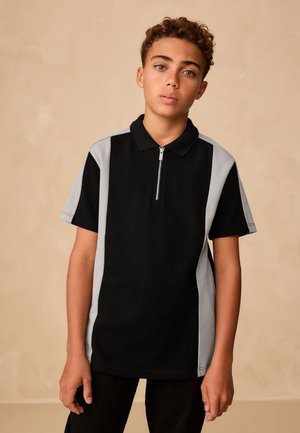 Sort polo-shirt med grå sideaccenter, korte ærmer og lynlåslukning i halsen. Fremstillet af bomuld med en glat tekstur.