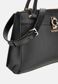 Borsa a mano in pelle nera con finitura texture, hardware dorato, manici superiori e tracolla staccabile. Presenta un dettaglio del logo sulla parte anteriore.