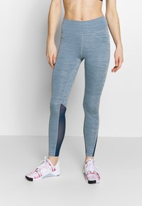 Světle modré sportovní legíny s texturovaným vzorem a tmavomodrými síťovinovými akcenty po stranách, s vysokým pasem.