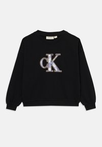 Sweatshirt noir avec un col rond et des manches longues. Présente un grand logo "ck" brodé en bleu et blanc à l'avant. Tissu doux.