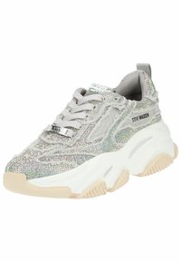 Chaussure de sport grise avec des embellissements en strass, un tissu texturé et une semelle blanche épaisse. Présente un design à lacets et des détails de logo.
