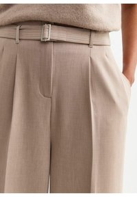 Beiga skräddarsydda byxor med en slät textur, utrustade med ett bälte med en silverfärgad spänne, sidofickor och plisserade detaljer.