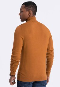 Rollkragenpullover aus senfgelbem Strickstoff, figurbetonter Stil mit langen Ärmeln und gerippten Bündchen. Rückansicht mit glatter Textur.