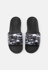 Sorte slidesandaler med en camouflert rem i grå og svarte nyanser, som har en teksturert såle og "Nike"-logoen preget på remmen.