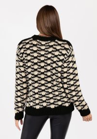 Dikke gebreide trui in zwart en crème met een textuur van bobbels, ronde halslijn en geribbelde zoom en mouwen.