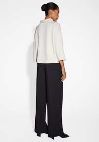 Maglione bianco testurizzato con colletto, maniche a tre quarti, abbinato a pantaloni neri lunghi, con una vestibilità comoda e un leggero luccichio.