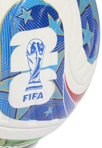 Zbliżenie białej piłki nożnej z niebieskimi i złotymi wzorami w kształcie gwiazdy oraz nadrukowanym niebieskim logo Pucharu Świata FIFA.