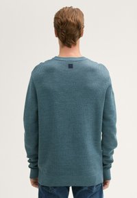 Hellblauer gestrickter Pullover mit Rundhalsausschnitt, gerippten Bündchen und Saum. Verfügt über ein kleines Logotag am hinteren Halsausschnitt. Weicher Stoff.