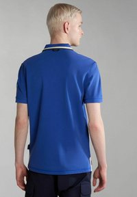 Polo shirt blu con colletto a contrasto, maniche corte e spacchi laterali. Realizzato in tessuto texturizzato, con un'etichetta in basso a sinistra.