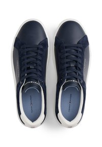 Tenisi Tommy Hilfiger de culoare bleu marin și alb, cu șireturi, dintr-un amestec de piele întoarsă și piele, văzuți dintr-un unghi superior care arată logo-ul brandului în interior și pe părțile laterale.