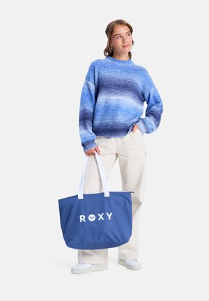 Zila un balta iepirkumu soma ar vārdu "ROXY" drukātām treknām burtiem. Izgatavota no izturīga materiāla, ar divām baltām rokturiem.