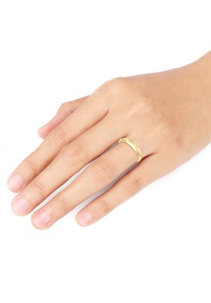 Gold-colored metal ring with a smooth, rounded band, worn on a hand with natural, unpolished nails against a white background.