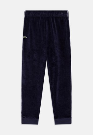 Navyblaue Velour-Trainingshose mit elastischem Bund, gerippten Bündchen, seitlichen Streifen und kleinem grünen Krokodil-Logo am linken Oberschenkel.