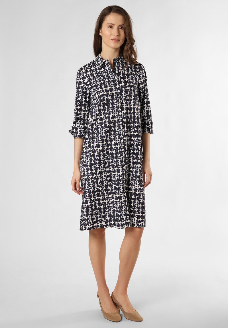 Shiffonkleid mit navyblauem und cremefarbenem Muster, mit Kragen, hochgekrempelten Ärmeln und lockerer Passform bis zur Mitte der Wade. Mit Knöpfen geschlossen.