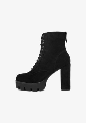 Čierne semišové členkové topánky s masívnym opätkom, šnurovaním vpredu, zaoblenou špičkou a platformovou podrážkou s textúrovaným dizajnom.