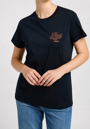 T-shirt en coton noir avec encolure ronde, manches courtes, et logo brodé rouge "Lee 1889" sur la poitrine. Texture lisse, coupe standard.