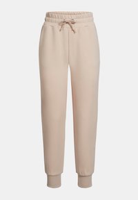 Beige träningbyxor i mjukt material, med elastisk midja och dragsko, samt ribbade muddar vid anklarna.