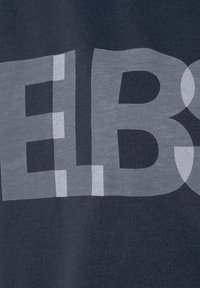 Dunkelblaues T-Shirt mit großem, halbtransparentem weißen Text auf der Brust. Der Stoff scheint weich und hat eine glatte Textur.
