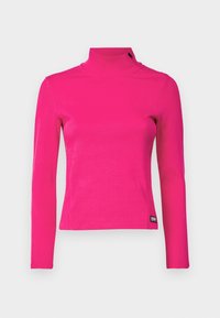 Upnutá dlouhá tričko s rolákem v jasně růžové žebrované tkanině, s minimalistickým designem a jemným detailem štítku na lemu.