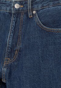 Mørkeblå denim jeans med et klassisk fem-lomme design, med gyldent sytråd og en metalknap-lukning i taljen.