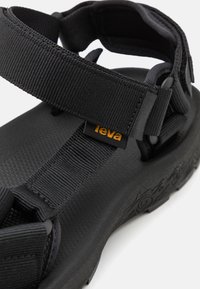 Musthave mustad, mille reguleeritavaid kangast rihmasid, tekstureeritud tallaga ja reljeefne muster taldadel. Omab väike kollane logo silt.