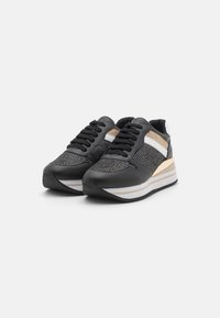 Sneakers neri con una tomaia texture e dettagli metallici, una suola imbottita prominente e strisce bianche e dorate a contrasto.
