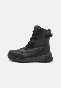 Schwarzer wasserdichter Stiefel mit abgerundetem Zehenbereich, strukturiertem Obermaterial, Schnürverschluss und Zuglasche an der Ferse. Verfügt über eine dicke Gummisohle für besseren Halt.